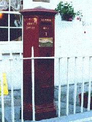  Maroon coloured hexagonal pillar box.